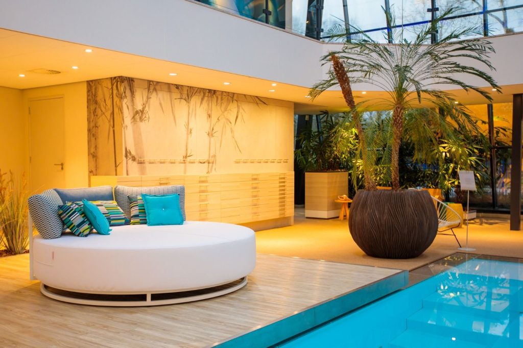 Wit rond ligbed bij een zwembad en een palmboom in een pot