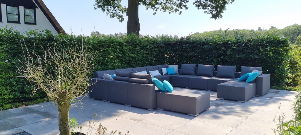 Zwarte loungeset met kussens voor een heg
