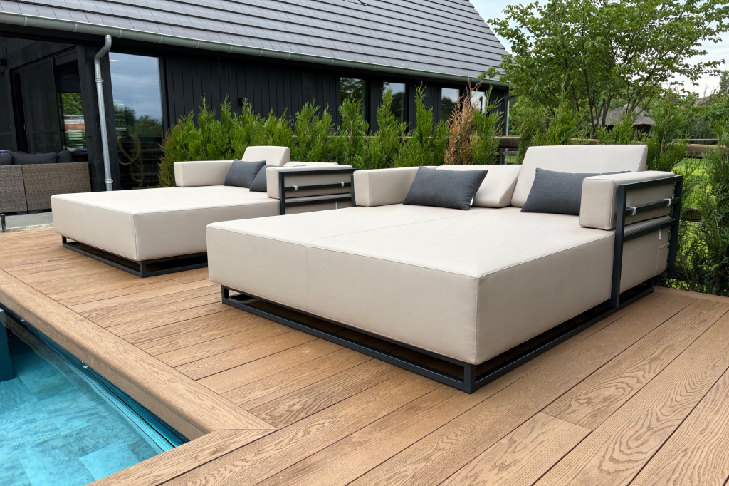 een beige loungebed aan een zwembad met struiken erachter