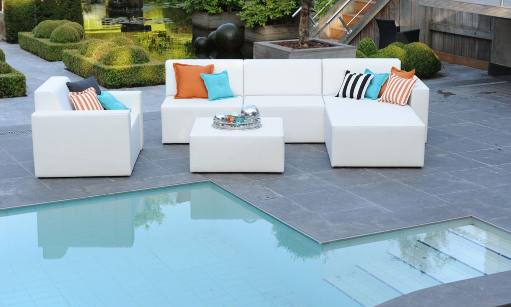 witte lounge set met een hocker en kussens aan een zwembad