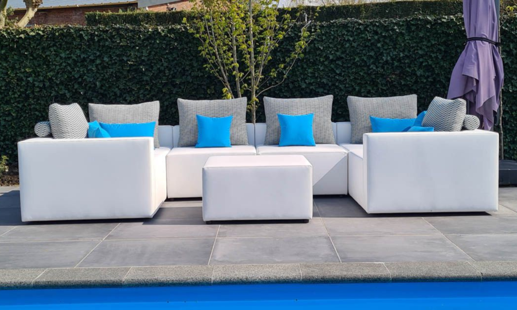 witte loungeset met hocker en kussen aan een zwembad
