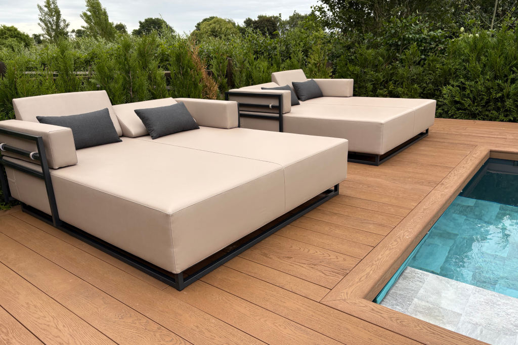 een beige lounge bed bij een zwembad met struiken